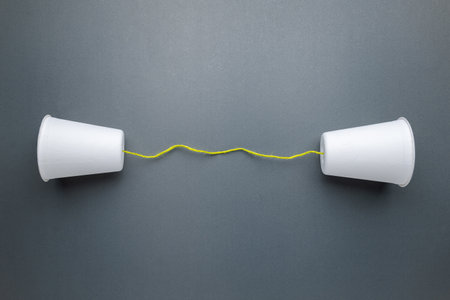 Two paper white cups with green string, old style cup phone, or toy phone for communication conceptの写真素材