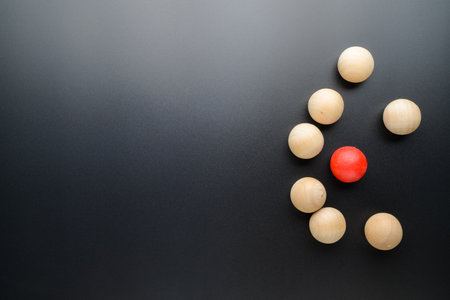 Small red ball is under seige of many wooden balls on black background, small business in competition, and enciclement, or niche, and different conceptの写真素材