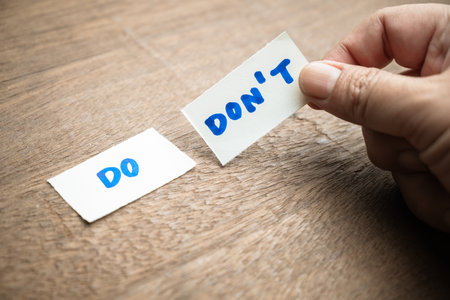 Do and Don't concept by two pieces of paper with handwriting text, closeup man takes a close look at...