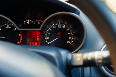 Closeup car dashboard with LED red light, showing parking brake icon, speed meter, fuel and temp...