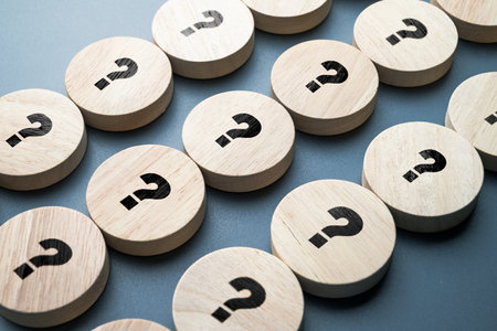 Many question marks on round wood blocks arranged in the rows, many questions need the answers,...