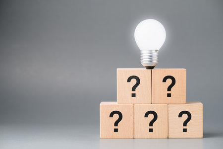 A light bulb glowing at the top stage with many questions as a base, creativity, and success, or innovative thinking, learn from mistakeの写真素材