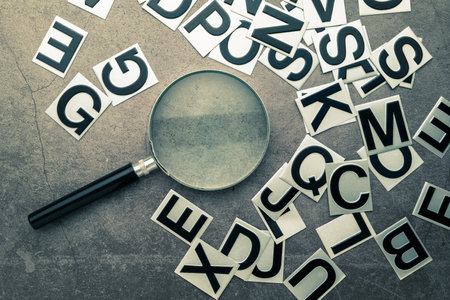 Magnifying glass and English alphabet stickers scattered on the table, glossary, words selection to communicate, searching, or learning English conceptの写真素材