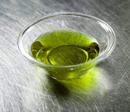 extra virgin olive oil in a little bowl on a stanless steel tableの写真素材
