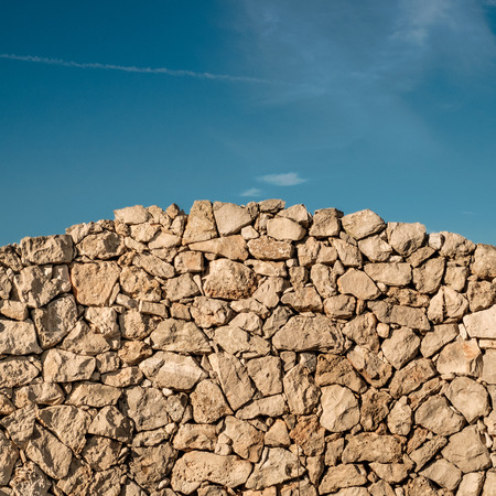 Arched dry stone wall with a blue sky on backgroundの写真素材