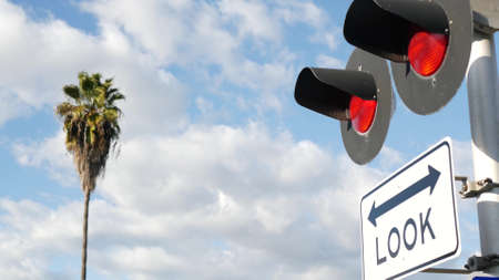 Level crossing warning signal in USA. Crossbuck notice and red traffic light on rail road...