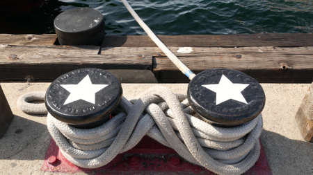 Tied rope knot on metallic bollard with stars, seafaring port of San Diego, California. Nautical...