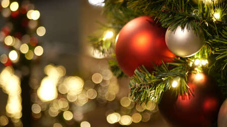 Closeup of Festively Decorated Outdoor Christmas tree with bright red balls on blurred sparkling...
