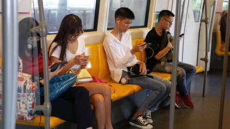 BANGKOK, THAILAND - JULY 13, 2019: Asian passengers in train using smartphones. Thai people online...