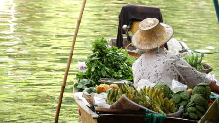 BANGKOK, THAILAND - JULY 13, 2019: Lat Mayom floating market. Traditional classic khlong river canal, local women farmers, long-tail boats with fruits and vegetables. Iconic asian street food sellingのeditorial素材