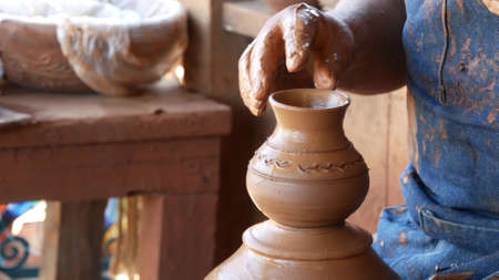 SAN DIEGO, CALIFORNIA USA - 5 JAN 2020: Potter working in mexican Oldtown, raw clay on pottery wheel. Man's hands, ceramist in process of modeling handcrafted clayware. Craftsman creating ceramic.のeditorial素材