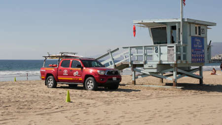 SANTA MONICA, LOS ANGELES CA USA - OCT 28, 2019: California summertime beach aesthetic. Iconic blue wooden watchtower, red lifeguard car on sandy sunny coast. Amusement park and attractions on the pierのeditorial素材
