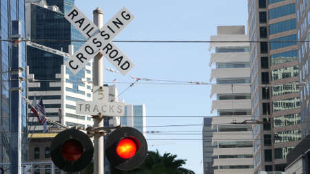 Level crossing warning signal in USA. Crossbuck notice and red traffic light on rail road intersection in California. Railway transportation safety symbol. Caution sign about hazard and train track.の写真素材