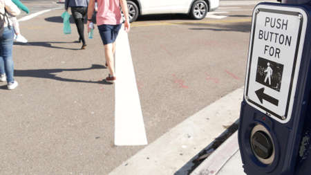 Traffic light button on pedestrian crosswalk, people have to push and wait. Traffic rules and regulations for public safety in USA. Zebra street crossing on road intesection in San Diego, California.の写真素材