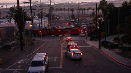 SAN DIEGO, CALIFORNIA USA - 15 JAN 2020: Level crossing near Lindbergh field international airport. Railroad tram and runway at sunset. MTS Trolley rail transportation, cars and railway transport.のeditorial素材