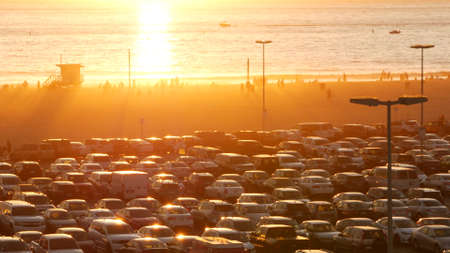 SANTA MONICA, LOS ANGELES, USA - OCT 28, 2019: California summertime beach aesthetic, atmospheric golden sunset. Unrecognizable people silhouettes, sun rays over pacific ocean waves. Lifeguard tower.のeditorial素材