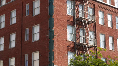 Fire escape ladder outside residential brick building in San Diego city, USA. Typical New York style...