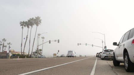 Encinitas, California USA -20 Feb 2020: Traffic light semaphore on highway 101 road by misty beach. Fog on sea shore, pacific ocean coast. Freeway with cars along shoreline, coastline near Los Angelesのeditorial素材