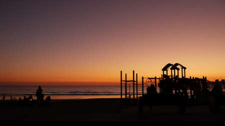 Oceanside, California USA - 8 Feb 2020: Silhouette of people making bbq campfire. Beachfront recreation area for barbeque with fire place on pacific ocean coast. Bonfire for barbecue on sunset beach.のeditorial素材