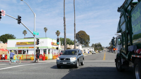 Oceanside, California USA -20 Feb 2020: Wienerschnitzel hot dog fast food, pacific coast highway 1, historic route 101. Palm trees on street, road along ocean. Green garbage truck on road intersectionのeditorial素材