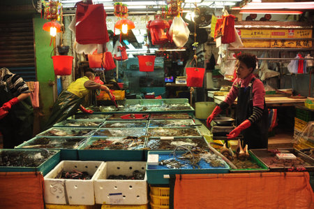 HONG KONG - 22th FEBRUARY, 2015: View of workers sorting fresh catch of seafood in different containers at stall outdoors. People sorting seafood at stallのeditorial素材