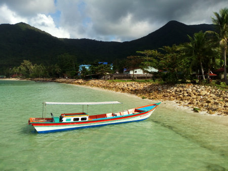 View of single floating fisherman boat in crystal water of tropical coastline with mountains and palms. Sailing boat in clear water of ocean. Koh Phangan exotic paradise islandのeditorial素材