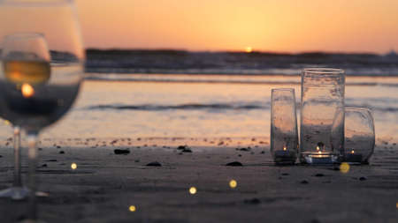 Candle flame lights in glass, romantic beach date by California ocean waves, summer sea water.の写真素材