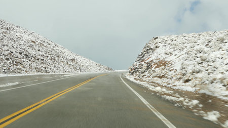 Road trip to Death Valley, driving auto, snow in California, USA. Hitchhiking winter traveling in America. Highway, mountain pass and dry barren wilderness. Passenger POV from car. Journey to Nevada.の写真素材