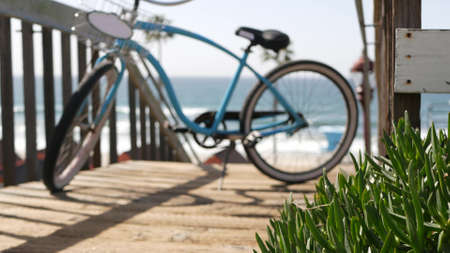 Blue bicycle, cruiser bike by ocean beach, pacific coast, Oceanside California USA. Summertime vacations on sea shore. Vintage cycle near wooden stairs, stairway access. Staircase, tropical palm treesの写真素材