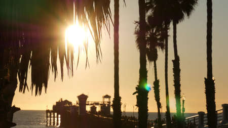 People walking wooden pier, California USA. Oceanside waterfront vacations tourist resort. Ocean beach summertime sunset atmosphere. Blurred crowd strolling on boardwalk. Seamless looped cinemagraph.の写真素材
