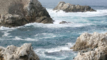 Rocky craggy dramatic ocean beach near Big Sur, 17-mile drive. Big blue waves crashing on cliff,...