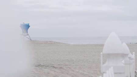 Lifeguard stand or life guard tower hut, surfing safety on California beach, USA. Rescue station, coast lifesavers wachtower or house, Coronado ocean beach, San Diego shore. White wooden picket fence.の写真素材