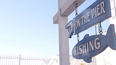Fishing on pier wooden blue sign, California ocean beach, USA. Coast recreation area on Crystal pier, Mission beach in San Diego. Signpost, signboard or signage by summer sea. Beachfront vacations.の写真素材