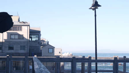 Waterfront wooden boardwalk in Monterey, California USA. Beachfront promenade on piles, pillars or pylons by ocean sea water and bay aquarium on Cannery Row street. Tourist vacations waterside resort.の写真素材