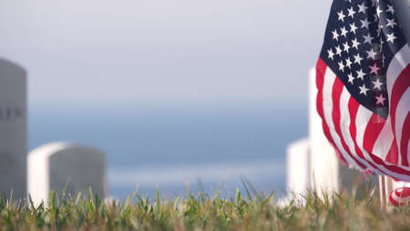 Tombstones and american flag, national memorial cemetery, military graveyard in USA. Headstones or gravestones, green grass. Respect and honor for armed forces soldiers. Veterans and Remembrance Day.の写真素材