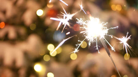 Sparkler firework burning, Christmas tree in snow, New Year or Xmas bengal light. Decorated spruce, pine or fir in snowflakes . Winter holiday fairy magic, sparkles glow, flakes and golden stars bokehの写真素材