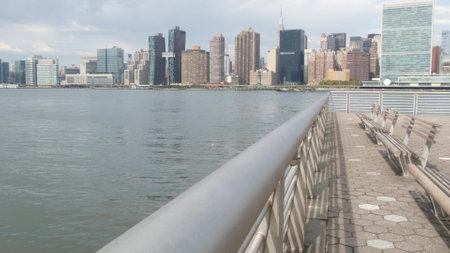 New York City waterfront skyline, Manhattan Midtown buildings, riverfront skyscrapers by East river water. Waterside cityscape, Gantry Plaza Park, Long Island, Queens, United States. Riverside bench.の写真素材