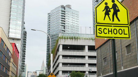 School zone yellow road sign, pedestrian crossing. Children safety, New York City street. Transport and education symbol, USA. Traffic roadsign, Queens, Long Island. Manhattan view, Chrysler Building.の写真素材