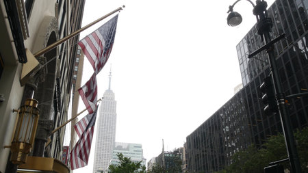 New York, american flag waving. Empire State Building. Manhattan midtown, 34 West city street....