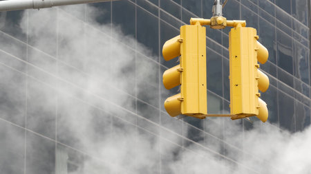 Steam vapor vented on New York City street, vapour tube stack. Hot smoke from pipe. Con Edisons Steam Operations system, Manhattan financial district architecture. Yellow traffic light, skyscraper.の写真素材