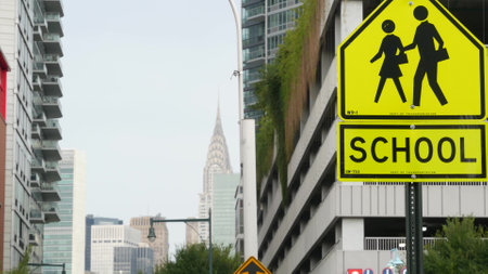 School zone yellow road sign, pedestrian crossing. Children safety, New York City street. Transport and education symbol, USA. Traffic roadsign, Queens, Long Island. Manhattan view, Chrysler Building.の写真素材