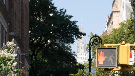 New York City Irving street crossroad, yellow pedestrian traffic light, transport road intersection, NYC Midtown, United States. Chrysler Building thru Gramercy Park greenery. Red hand stop signal.の写真素材