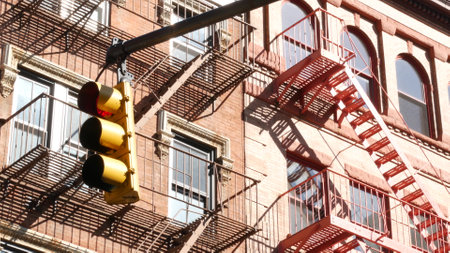 New York City street crossroad, yellow traffic light, transport road intersection, United States. Residential building architecture. NYC real estate, Red brown brick house with fire ladder. Manhattan.の写真素材