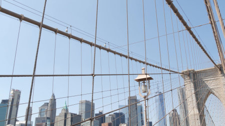 Brooklyn Bridge to Manhattan downtown, cables and blue sky. New York City skyline, financial district cityscape. World Trade Center, USA travel destination. Architecture of United States of America.の写真素材