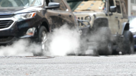 Hot smoke from manhole, Steam system in New York City, United States. Vapor from road on Beaver Street, NYC Downtown Financial District, Lower Manhattan, USA. Urban scene, low angle. Carsの写真素材