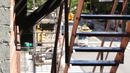 New York City classic building architecture. Urban residential house exterior, USA. Typical brick facade. Fire escape ladder. Chelsea district, high line, 10 avenue. Street crossroad, yellow taxi cab.の写真素材