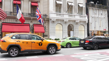 New York City, United States - 11 Sept 2023: Manhattan Midtown street, Fifth 5 avenue. American urban road car traffic. Yellow and green boro taxi. People. Boutique fashion luxury stores, USA shoppingのeditorial素材