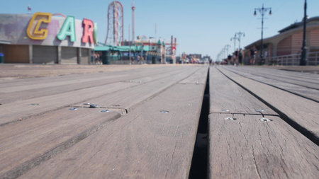 Coney Island beach promenade in Brooklyn, New York, United States. Wooden boardwalk near retro luna park. Amusement park on ocean coast beach. Waterfront summer holiday, people walking on promenade.の写真素材