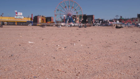 Coney Island sandy beach in Brooklyn, New York, United States. Boardwalk near retro luna park. Ferris wheel in american amusement park on ocean coast. Waterfront summer holiday promenade in NYC, USA.の写真素材