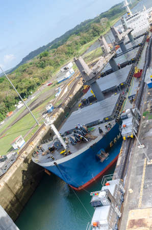 Oil tanker, assisted by tugboats, are preparing to transit the Panama Canal to the west towards the...